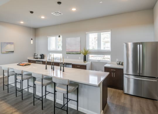 an open kitchen with a large island and stainless steel refrigerator