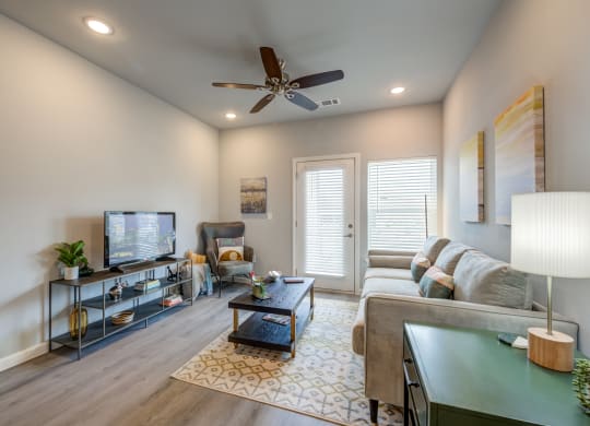 a living room with a ceiling fan and a tv