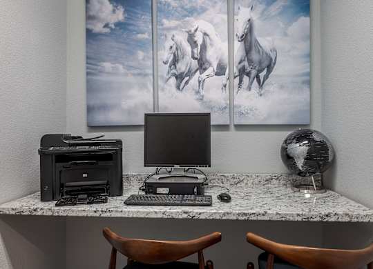 a desk with a computer and three pictures of horses on the wall