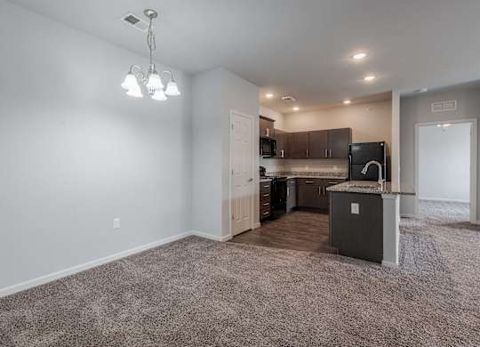 an empty living room with a kitchen in the corner