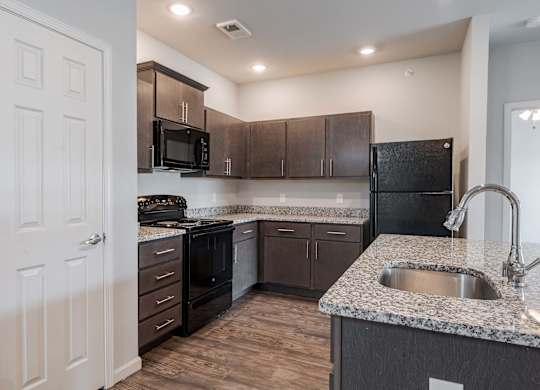 a kitchen with granite counter tops and black appliances