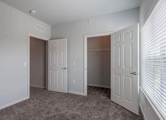 an empty bedroom with two doors and a closet