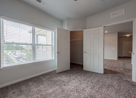 an empty bedroom with a large window and a closet