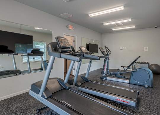 a gym with cardio equipment and a flat screen tv