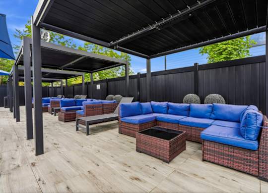 Covered outdoor lounge with blue sectional seating at The Franklin at Marlboro Apartments, Marlboro, 07746