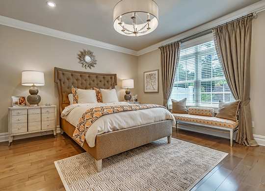 A bedroom with a large bed and a bench by the window.