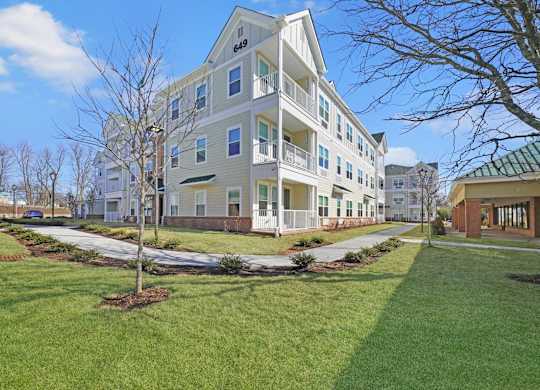 a large apartment building with a lawn and sidewalk in front of it at The Franklin at Hillsborough Apartments, Hillsborough, NJ 08844