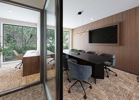 A conference room with a long table and chairs, a television on the wall, and a view of trees outside the window.