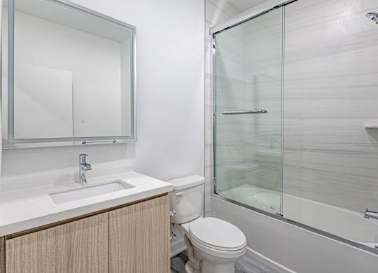 A white bathroom with a toilet, sink, and shower. at The Franklin at Marlboro, New Jersey, 07746