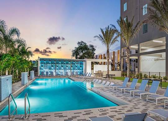 a swimming pool with a bunch of chairs around it at Elements on Third Apartments, Florida