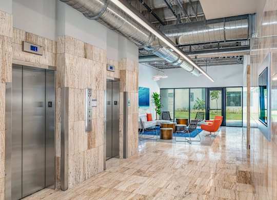 the lobby of a building with elevators and a table and chairs at Elements on Third Apartments, Florida, 33713