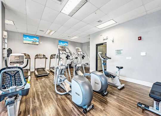 a gym with cardio machines and a mirror in the corner at Elements on Third Apartments, St. Petersburg, FL