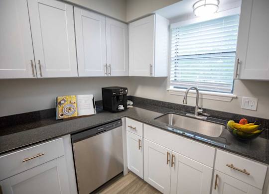 A kitchen with white cabinets and a black countertop.