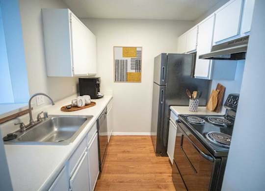 A kitchen with a stove, sink, and refrigerator.