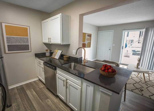A kitchen with white cabinets and a black countertop.