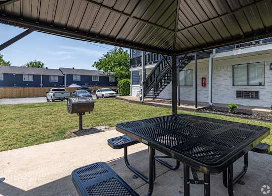 A black table and two black chairs are on a patio.