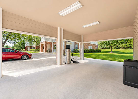 A red car is parked in a garage with a black box on the floor.