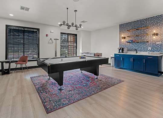 A pool table is in the middle of a room with a rug on the floor.