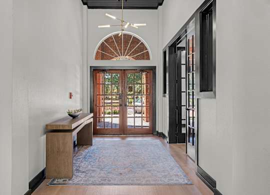 A hallway with a wooden bench and a rug on the floor.