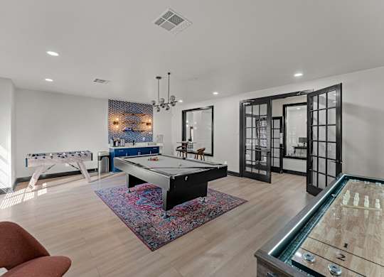 A room with a pool table and a foosball table.