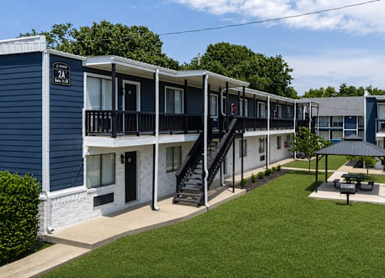 A blue and white building with a black staircase leading to the second floor.