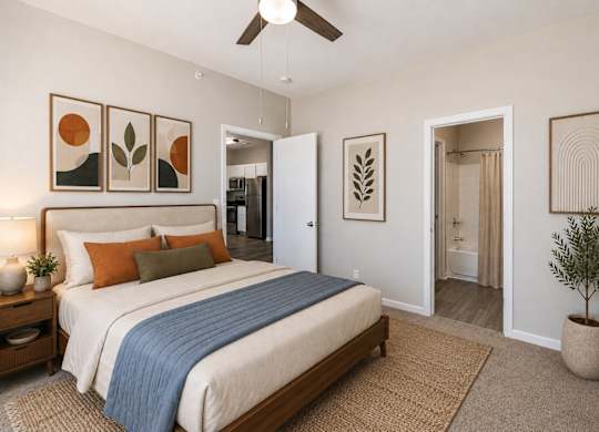 A bedroom with a bed, a ceiling fan, and a plant.