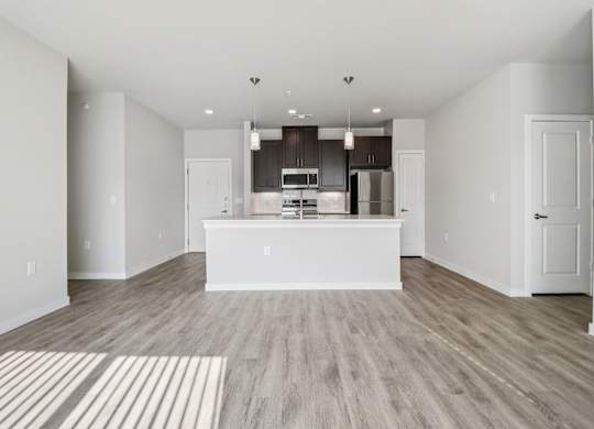 A modern kitchen with a white island and wooden floors.