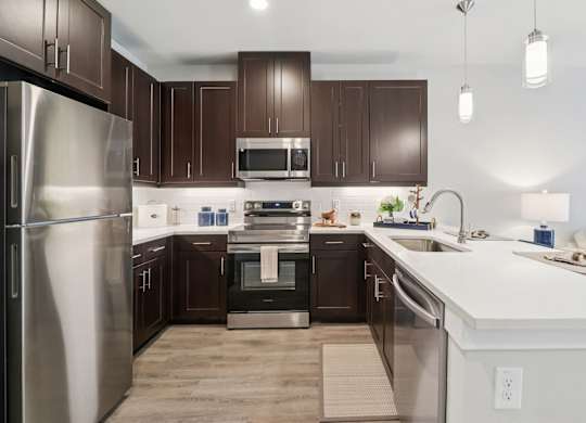 A modern kitchen with dark brown cabinets and stainless steel appliances.