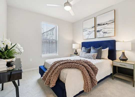 A bedroom with a bed, nightstand, and a painting on the wall.
