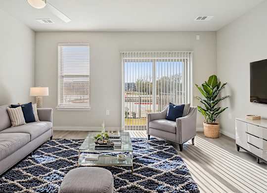 A living room with a grey couch, a glass coffee table, and a painting on the wall.