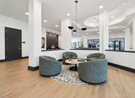 A modern living room with a black door and grey armchairs.