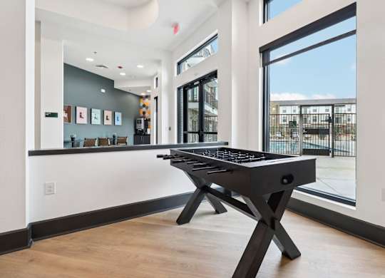 A black pool table in a room with a view of the outside.