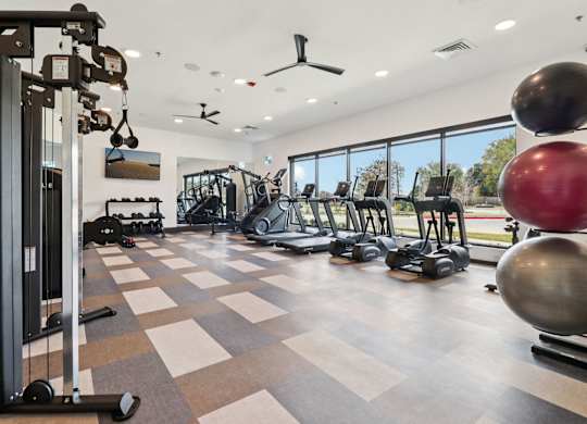 A gym with a variety of equipment including a weight machine, a treadmill, and a rowing machine.
