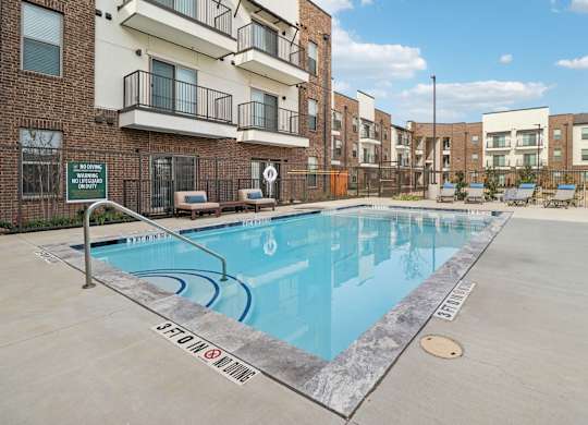 A swimming pool in a residential area surrounded by apartment buildings.