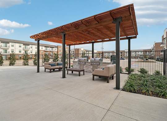 A patio with a wooden pergola and cushioned seating.