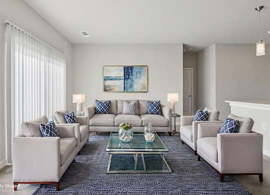 A living room with a large couch, two armchairs, and a coffee table.