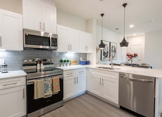 A modern kitchen with white cabinets and stainless steel appliances.
