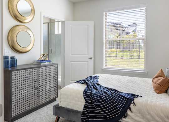 A bedroom with a bed, a dresser, and two round mirrors on the wall.