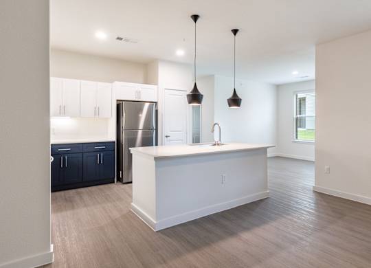 A kitchen with a white island and a refrigerator.