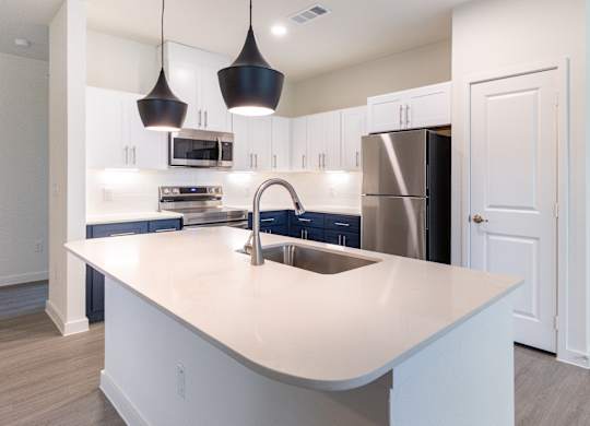 A modern kitchen with a large island and stainless steel appliances.