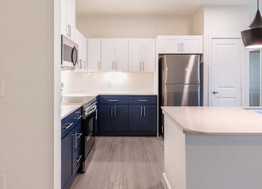 A kitchen with white cabinets and a stainless steel refrigerator.