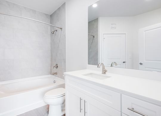 A white bathroom with a toilet, sink, and bathtub.
