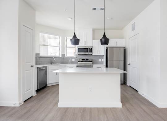 A modern kitchen with a white island and pendant lights.