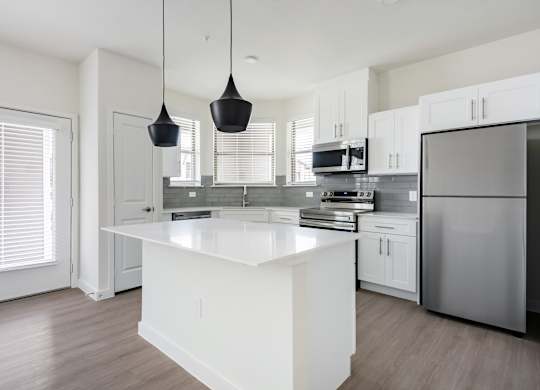 A modern kitchen with a white island and stainless steel appliances.