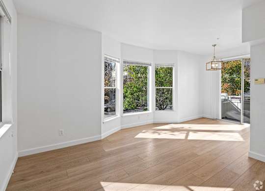 A large, empty room with wooden floors and white walls at Westmont Place Townhomes Apartments, California, 95060
