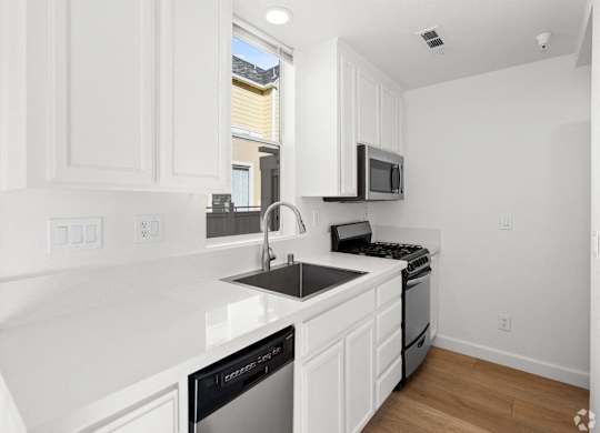 A kitchen with white cabinets and black appliances. at Westmont Place Townhomes Apartments, Santa Cruz, 95060