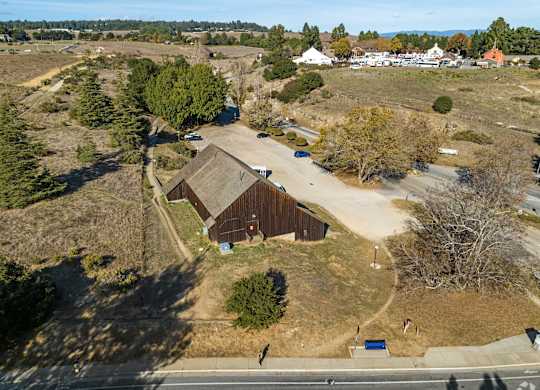 A large barn sits in the middle of a field with a road running in front of it at Westmont Place Townhomes Apartments, Santa Cruz, CA, 95060