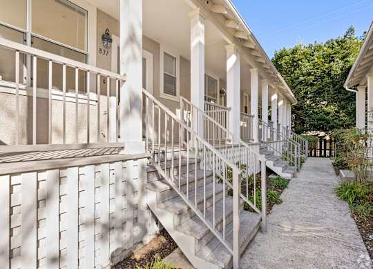 A white building with a balcony and steps leading to the front door at Westmont Place Townhomes Apartments, Santa Cruz, CA