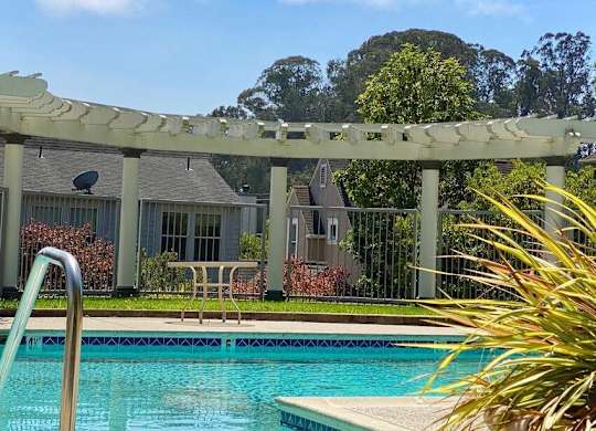 A pool with a slide and a house in the background at Westmont Place Townhomes Apartments, Santa Cruz