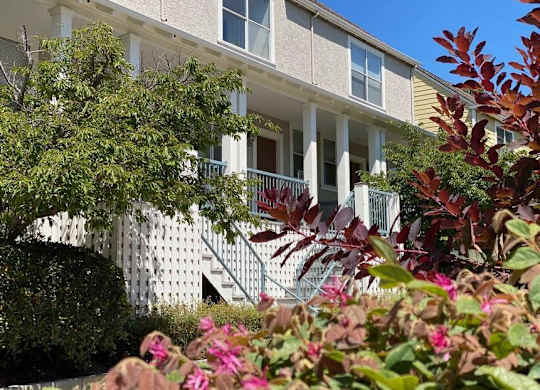 A white building with a balcony and a white picket fence at Westmont Place Townhomes Apartments, Santa Cruz, California